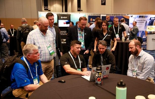Construction procurement professionals networking around a laptop at a conference
